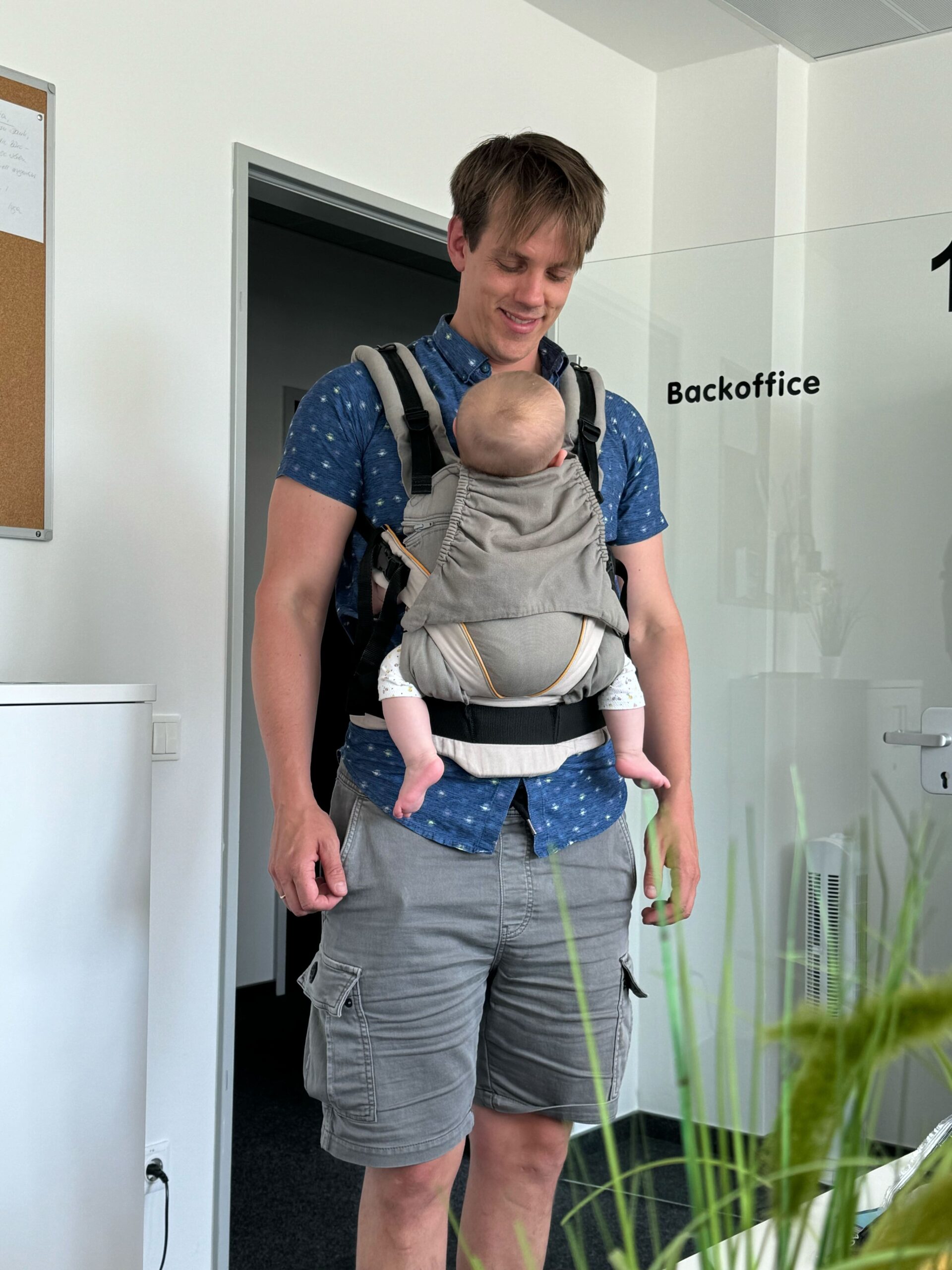 An employee carries his baby in a baby carrier outside the backoffice door